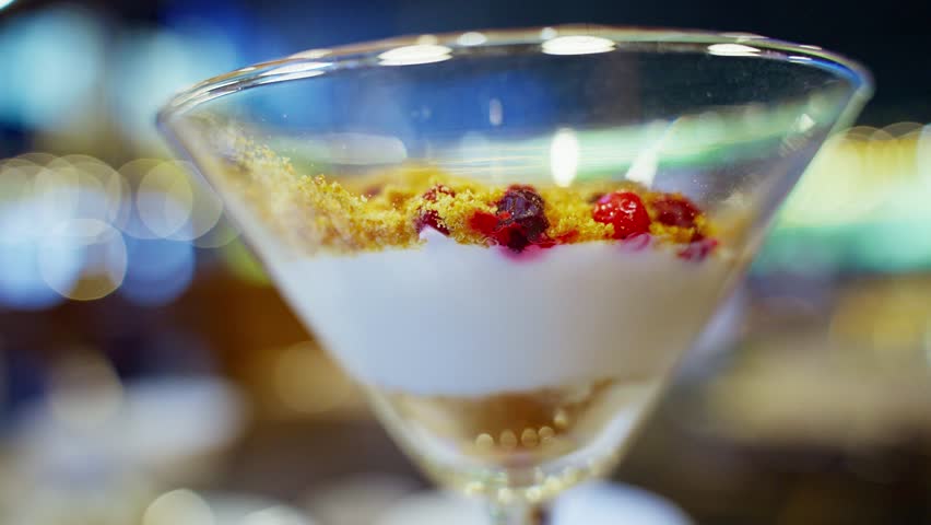 A close-up shot of a dessert being served at a cafe. The dessert features a creamy base, topped with crumble and berries.