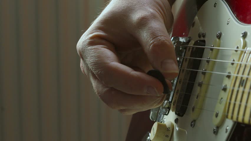 Close Up of Male Hand Playing Red Electric Guitar in Slow Motion 100 FPS with Plastic Plectrum Pick on High Notes