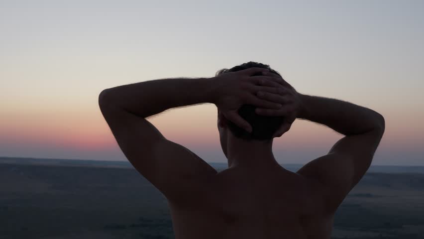 Man watching sunset from top of Bruneau Sand Dunes.  Shot on a mirrorless camera.  Tall sand dunes located in Idaho in the western part of the United States.  Silhouette.