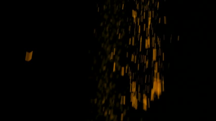 Abstract black background with a stream of slowly pouring orange turmeric powder.