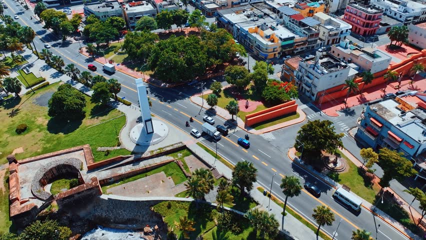 Aerial view of oceanfront expressway. The coastal city bathes in the golden light of the setting sun. The stone embankment is washed by sea waves. The sea city of Santo Domingo, Dominican Republic.