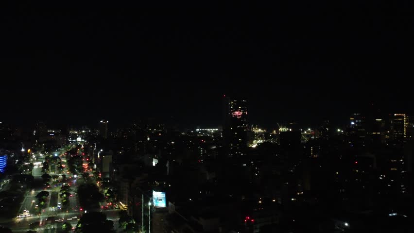 Drone view of Buenos Aires at night, highlighting the vibrant lights and bustling activity around Avenida 9 de Julio, showcasing the city