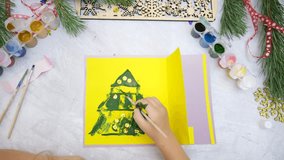 Child making a greeting card,  painting fingers, Craft for children, Nice paper card with Chrictmas tree in yellow gray and green colours, decorating golden beads Top view - Powered by Shutterstock - Get 15% off with code: PIKWIZARD15