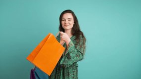 Happy woman showing shopping bags in blue studio - Powered by Shutterstock - Get 15% off with code: PIKWIZARD15