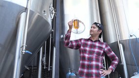 A Man tasting craft beer In the back is a large brewery with the concept of making your own craft beer. - Powered by Shutterstock - Get 15% off with code: PIKWIZARD15