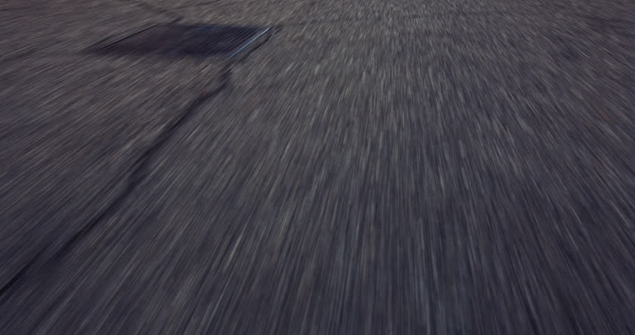 Motion blur footage of a road with visible markings and cracks, conveying speed and movement.