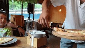waiter serving cheesepizza for family in restaurant putting slices on tables. Family weekend - Powered by Shutterstock - Get 15% off with code: PIKWIZARD15