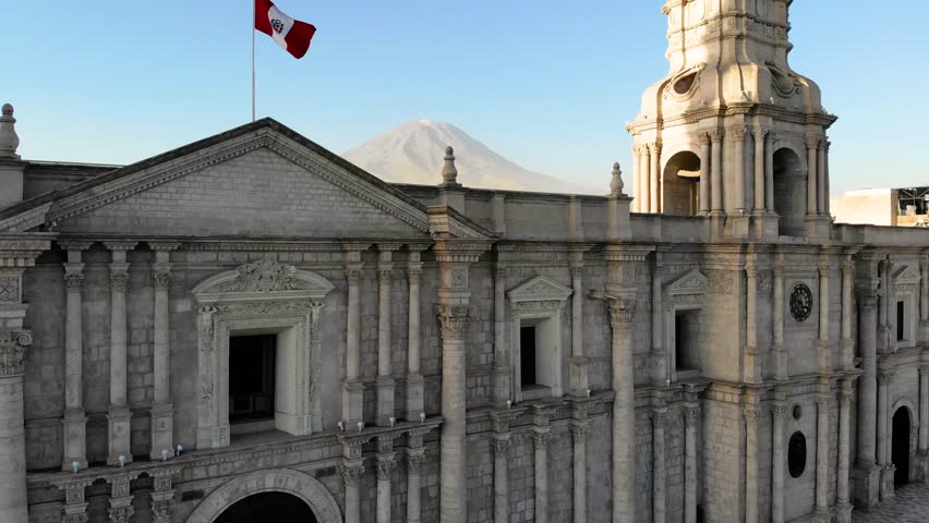 
aerial view of the cathedral of Arequipa with the national flag of Peru and the Misti volcano in the background