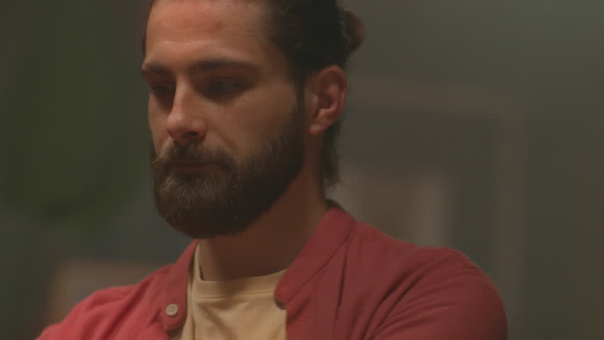 Energetic moving around tracking shot of good-looking young Caucasian man wearing headphones and listening to music. Attractive guy imitating playing musical instrument and singing. Close-up. Evening
