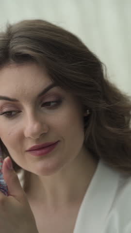 The girl lies down on the bed admiring herself in a small hand mirror, she does her makeup. She is in love, she is waiting for a couple.