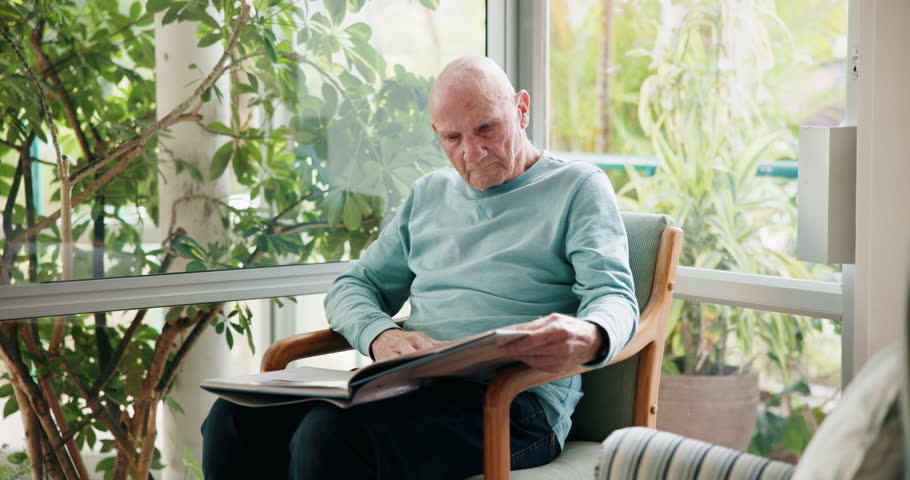 Home, relax and senior man with photo album, memory and retirement with nostalgia, grief and loss. Apartment, pensioner and mature guy with picture, gratitude and missing a loved one and photos