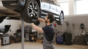 Male mechanic fixing tire of elevated car in modern auto repair shop. Professional auto service technician working with tools in garage. Vehicle maintenance and repair concept. - Powered by Shutterstock - Get 15% off with code: PIKWIZARD15