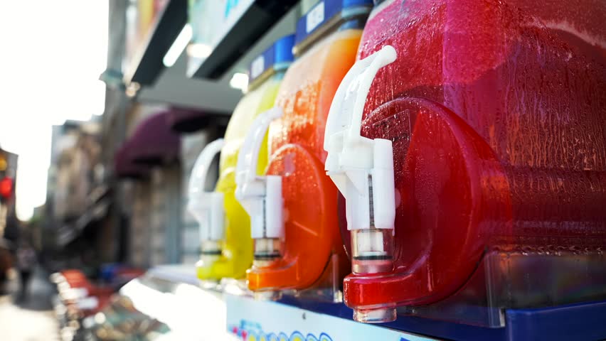 Close up of colorful frozen fruit juice drink mixing in dispenser machines on the Istanbul street in the summer at sunset. Concentrate drinks and sugar world problem