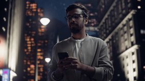 Indian Man Using His Smartphone on a Vibrant, Illuminated City Street at Night. Male Chatting with Friends in a Messenger App, Checking Work Emails, Browsing Internet and Online Shopping - Powered by Shutterstock - Get 15% off with code: PIKWIZARD15