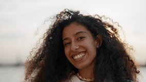 Beautiful female face with charming broad smile, Arab girl looking at camera. Portrait of joyful young adult woman on city quay in summer vacation, bright sun and positive emotions, happiness and joy - Powered by Shutterstock - Get 15% off with code: PIKWIZARD15