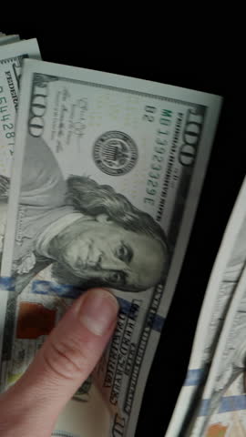 Vertical video. Hundred-Dollar Banknotes Counted By Female Hands, Camera Getting Closer Passing Through The Dollars.