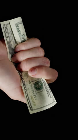 Vertical video. A Stack Of Twenty-Dollar Bills Flying Away In The Wind From Hands, Managing To Catch Only The Last Bill. Concept Of Stopping Empty Spending In Time.