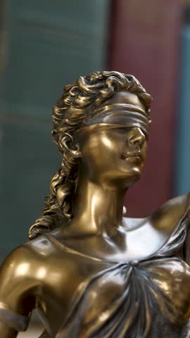 Statue of themis or lady justice. Femida on books background. Lawyer, law library concept. Blurred books, setting of knowledge or law. Impartiality and justice