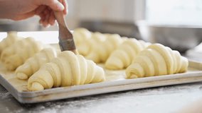 Prepare croissant for bake in oven. Female baker smears raw croissants with a brush. Cooking process - Powered by Shutterstock - Get 15% off with code: PIKWIZARD15