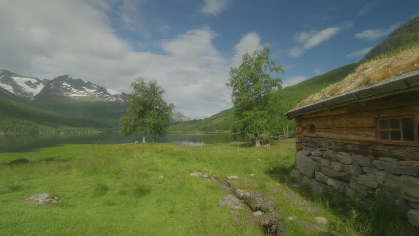 A young couple hiking near a rustic cabin in scenic Innerdalen, Norway on a sunny day