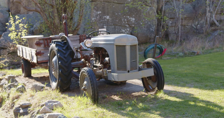 A slow-motion footage of an old cargo tractor parked on the grass on a sunny day