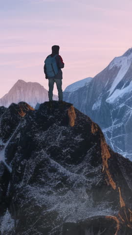 HIker Standing on Top of a Mountain Peak Looking at  Panorama of Mountains.