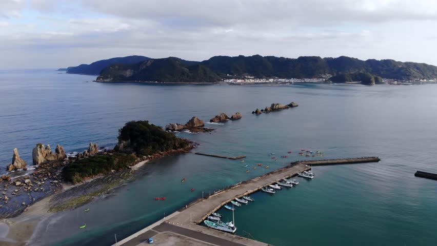Drone pan shot from right to left of Hashigui-Iwa rocks in Wakayama, Japan. Stunning geological formations and blue waters, ideal for travel documentaries, nature films, and promotional videos.