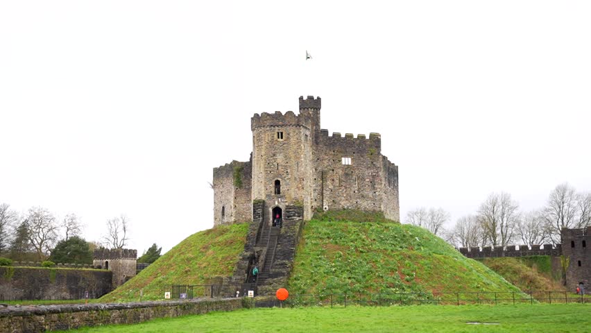 Tourists visiting old Norman Keep on top of artificial motte at Cardiff Castle during overcast day, Wales