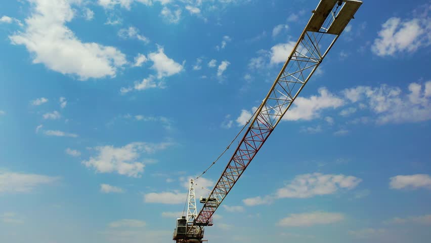 Crane tower in construction site. Industry construction concept footage. Drone view moving up around crane tower in construction site. Crane tower on city background. 