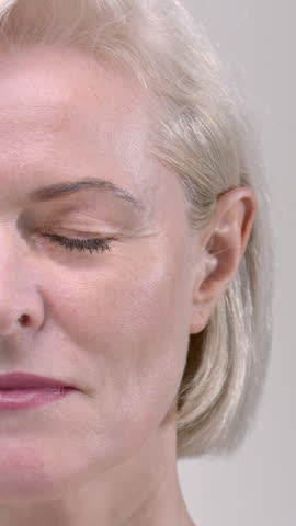 Half Portrait of an old woman in a white studio. The senior female is smiling with gray hair. Beautiful eyes, lips and teeth. The face of an elderly mature pensioner.