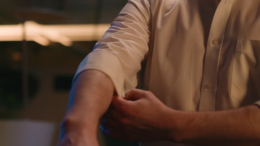 Cropped view unrecognizable unknown man stylish fashionable businessman style cloth luxury clothes roll sleeves and adjust collar of formal shirt fashion prepare date business male guy in evening room