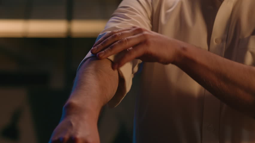 Cropped view unrecognizable unknown man stylish fashionable businessman style cloth luxury clothes roll sleeves and adjust collar of formal shirt fashion prepare date business male guy in evening room