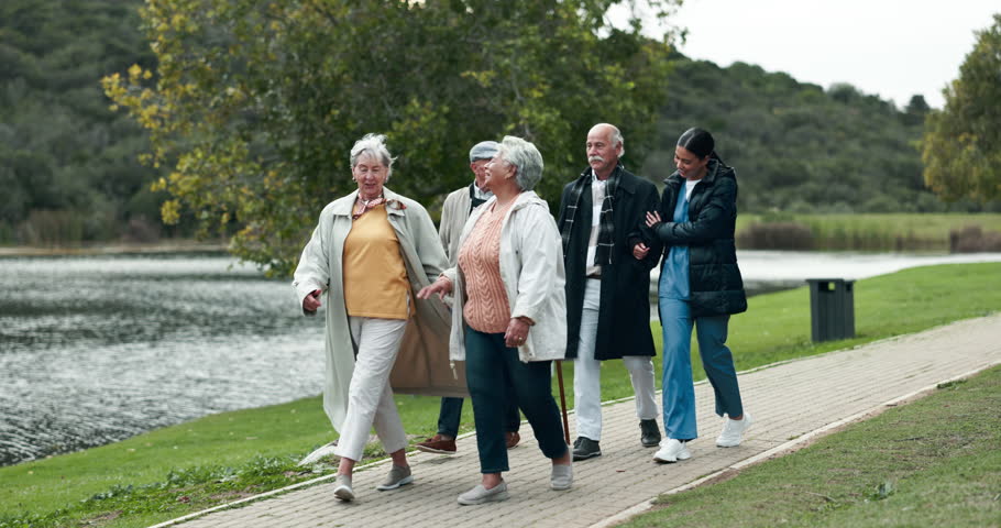 Assisted living, community and nurse walking with old people outdoor together for activity. Healthcare, friends or fresh air and senior group in garden with happy caregiver for medical wellness