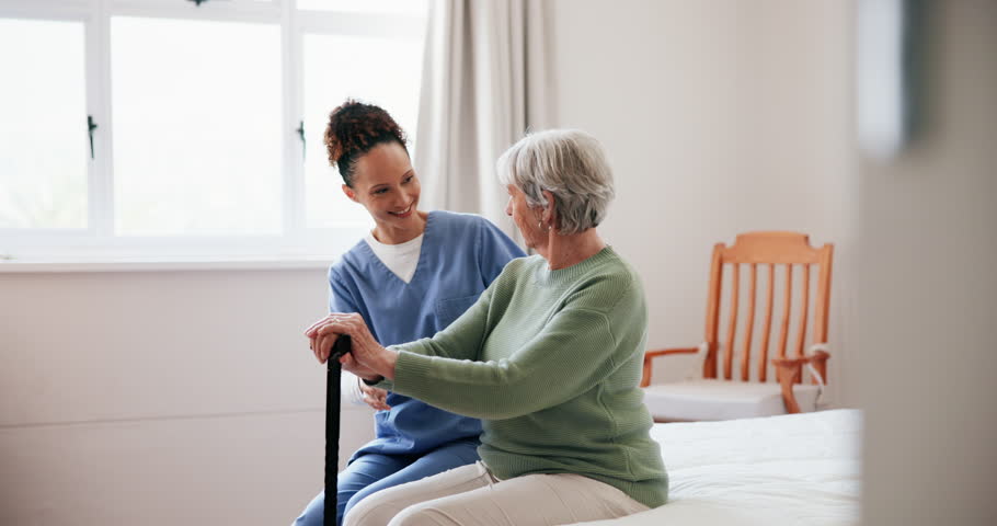 Caregiver, senior woman and help in bedroom at nursing home with cane for walking. People, nurse and pensioner in conversation at retirement house for support, care and healthcare with smile