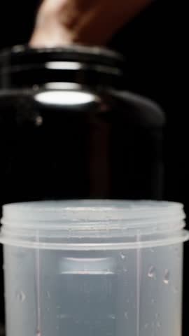 Vertical video. Pouring Protein Powder into a Cup of Water. Slow-Motion, Shaker on Black Background, Pre-Workout Preparation.
