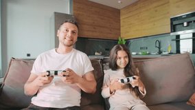 A father and daughter are sitting on the couch in their stylish living room, engaged in a competitive video game. The daughter triumphs in the game, celebrating her victory with her supportive dad. - Powered by Shutterstock - Get 15% off with code: PIKWIZARD15