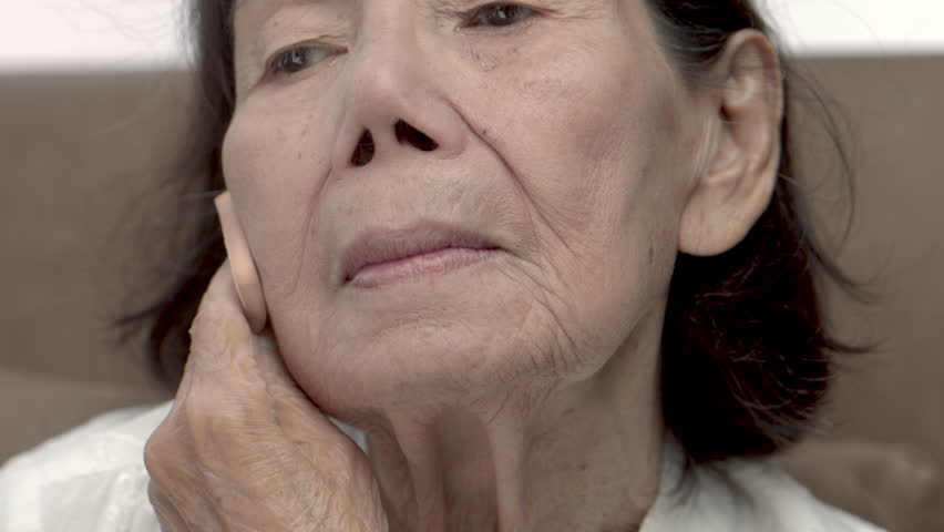 Close up of senior woman applying face powder with care giver in nursing home.