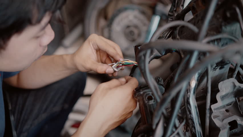 Mechanic repair or wiring motorcycle in garage. Repair or maintenance concept.