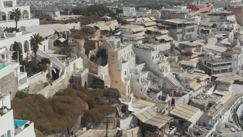 Aerial panorama of white houses, villas in Fira, Santorini Island, Greece. Thira city. Aegean Sea, Mediterranean. Panoramic aerial drone view from above
