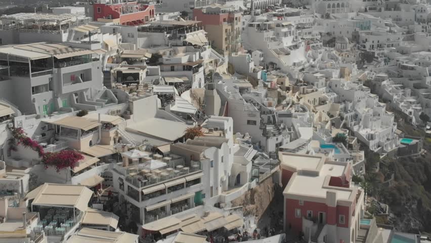 Aerial panorama of white houses, villas in Fira, Santorini Island, Greece. Thira city. Aegean Sea, Mediterranean. Panoramic aerial drone view from above
