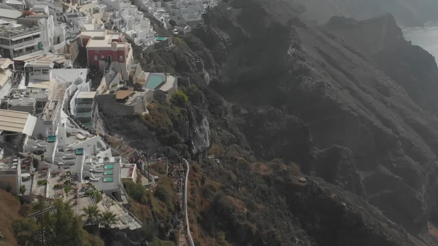 Aerial panorama of white houses, villas in Fira, Santorini Island, Greece. Thira city. Aegean Sea, Mediterranean. Panoramic aerial drone view from above

