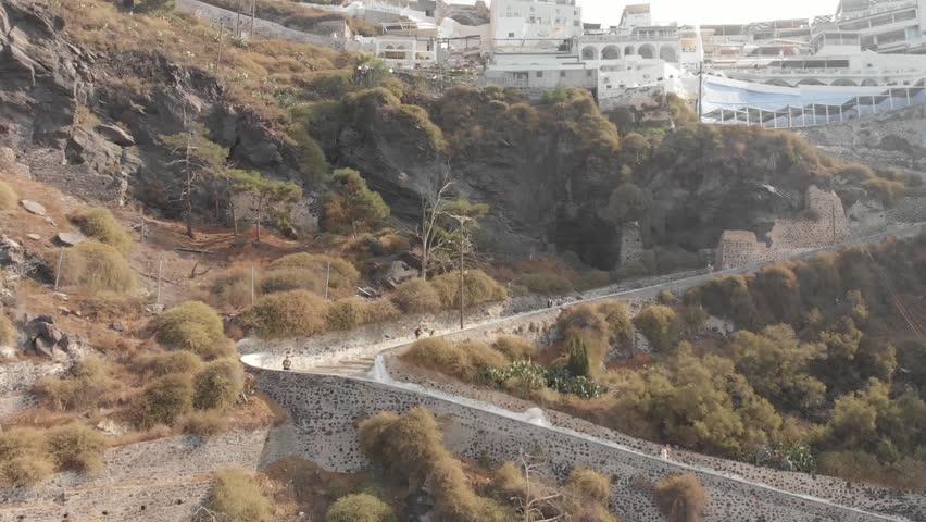 Aerial panorama drone view from above of path road from the port to the top which can be walked or ridden by horse or donkey. Fira, Santorini Island, Greece. Thira city. Aegean Sea, Mediterranean.
