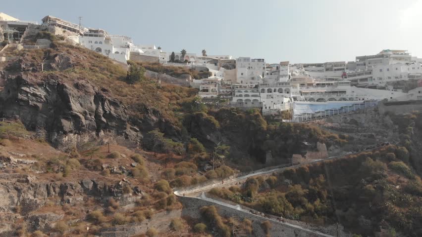 Aerial panorama drone view from above of path road from the port to the top which can be walked or ridden by horse or donkey. Fira, Santorini Island, Greece. Thira city. Aegean Sea, Mediterranean.
