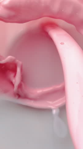 VERTICAL VIDEO POV super slow-motion of pouring strawberry cocktail into glass in white background. Tasty milkshake with protein and vitamin, top view, soft drinks in bar or restaurant, diet nutrition