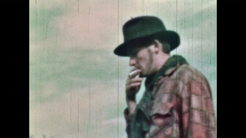 Happy cowboy smoking on natural summer landscape backdrop. Smiling man with valuable documents, money. Old American western style in countryside. Vintage color film. Wild West Retro 1960s archive