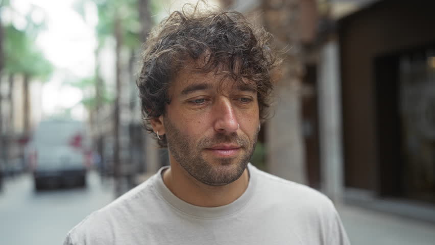 Young man smiling outdoors in an urban street, showcasing an attractive portrait of a hispanic male adult in a city setting