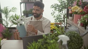 Smiling bearded man arranges flowers in a vase during a video call in a vibrant indoor flower shop. - Powered by Shutterstock - Get 15% off with code: PIKWIZARD15