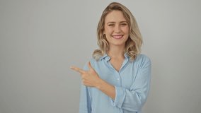 Cheerful young blonde woman wearing shirt, naturally expressing happy emotion with a smug smile while pointing up with a finger at the side. stands isolated against a plain white background. - Powered by Shutterstock - Get 15% off with code: PIKWIZARD15