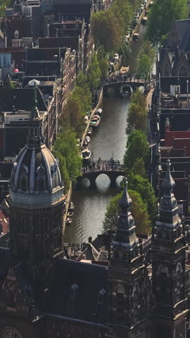 Amsterdam city of Netherlands. Aerial view of canals with electric boats in the center city. Drone view Amsterdam spring cityscape narrow old houses, canals. Establishing shot old centre aerial view