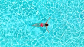 Aerial view of a woman in red swimsuit swimming in the pool. Summer lifestyle - Powered by Shutterstock - Get 15% off with code: PIKWIZARD15